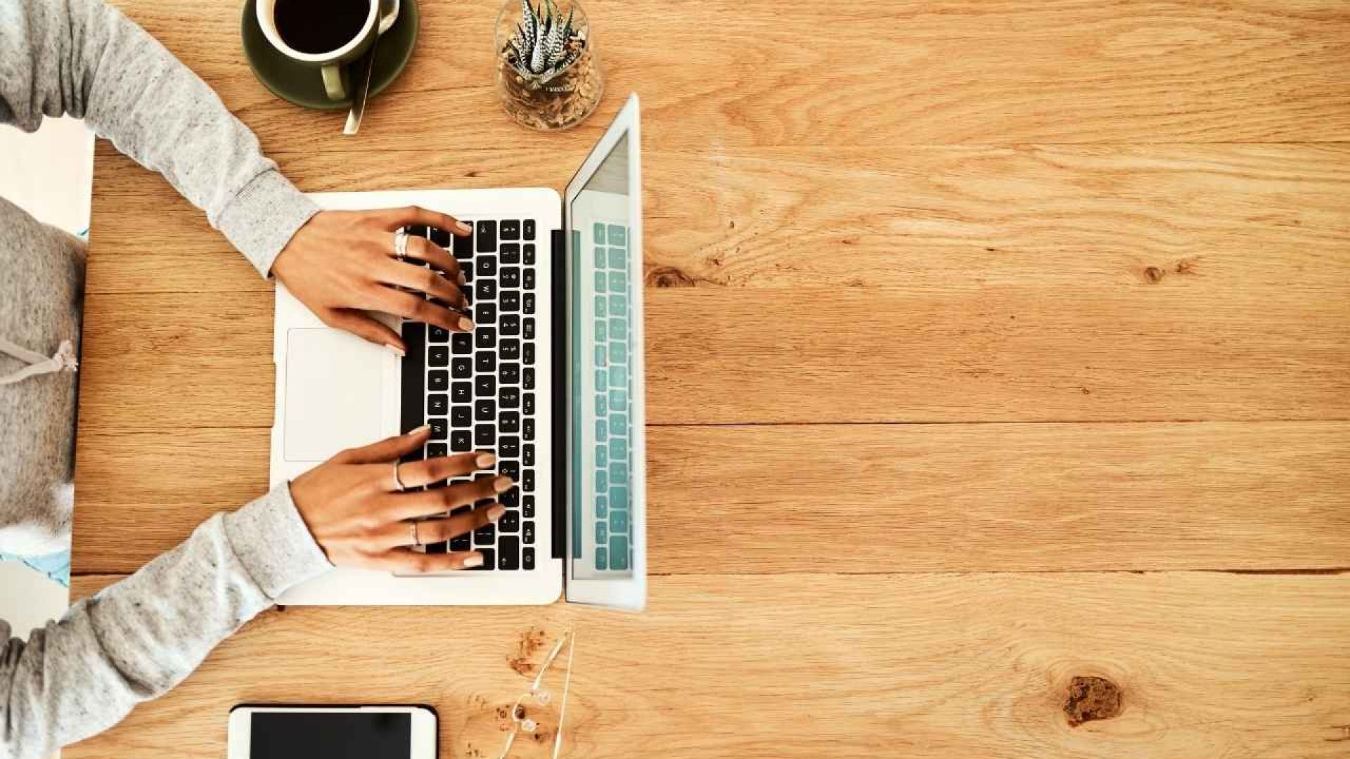 Person working on a laptop at a desk with a coffee cup